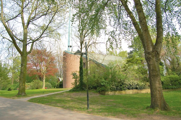 Das Gebäude der Kirche der St. Lukas-Kirche wird gezeigt. Die Kirche steht inmitten von vielen Bäumen