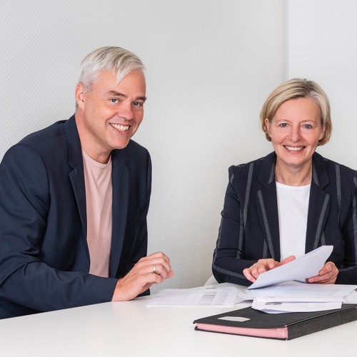 Zwei Männer und eine Frau sitzen am Tisch