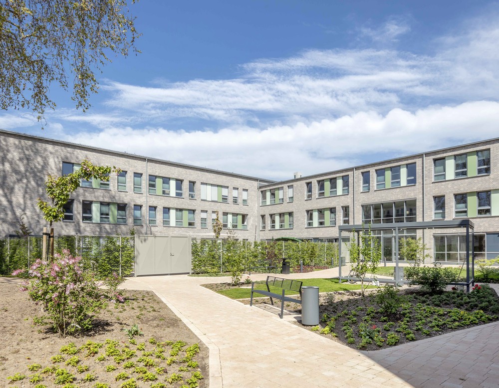 Titelfoto des Fortbildungsprogramms, Hauptgebäude der LWL-Klinik Münster, ein sandbeiger Weg führt auf das hellgraue Gebäude zu