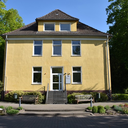 Hellgelbes zweistöckiges Gebäude des LWL-Rehabilitatioszentrums Münsterland im Sommer